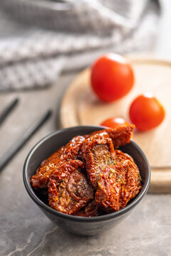 Sun-Dried Tomatoes in Bowl with Fresh Tomatoes on Wooden Board in Rustic Kitchen Setting