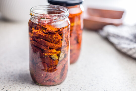 Jar Of Sun-Dried Tomatoes Preserved In Oil On A Kitchen Countertop, Close-Up