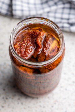 Jar Of Sun-Dried Tomatoes Preserved In Oil On A Kitchen Countertop, Close-Up