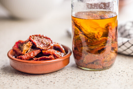 Sun-Dried Tomatoes in Olive Oil in Ceramic Bowl with Jar and Checkered Cloth