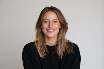 Obraz premium Joyful female portrait in a minimal studio setting with a warm, confident expression