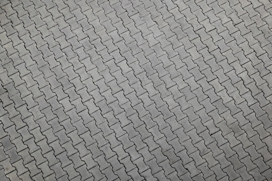 Gray interlocking pavement bricks forming a textured pattern suitable for outdoor surfaces.