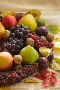 Fresh green pear with grapes autumn leaves and walnuts in harvest still life