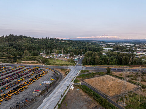 Tacoma, United States - 02 August 2026: Aerial view of the Port of Tacoma featuring rows of heavy construction machinery, industrial infrastructure, and a distant mountain.