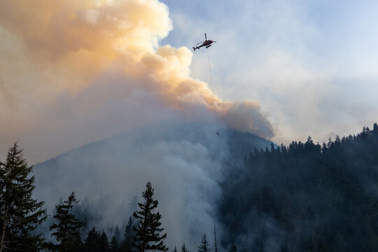 Helicopter Fighting Wildfire Over Smoke-Filled Forest Near Hope, BC Canada