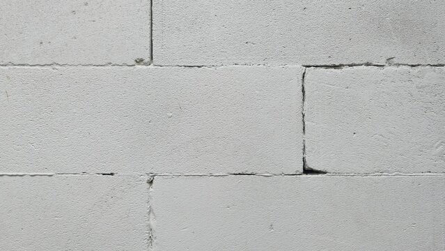 Old lightweight concrete block wall with wide gaps texture. Distressed unplastered cinder block masonry pattern, displaying deep separation lines and realistic aging for design.