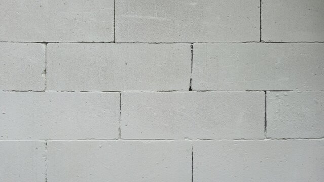 Old lightweight concrete block wall with wide gaps texture. Distressed unplastered cinder block masonry pattern, displaying deep separation lines and realistic aging for design.