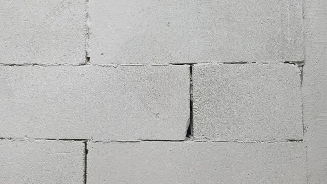 Old lightweight concrete block wall with wide gaps texture. Distressed unplastered cinder block masonry pattern, displaying deep separation lines and realistic aging for design.