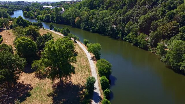 Forward drone fly over winding Mayenne River flowing through lush green forest and rural countryside landscape near Change, Mayenne, France