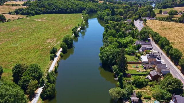 Forward panorama drone fly of peaceful Mayenne River landscape passing beside farmland and small Change rural commune, Mayenne, France