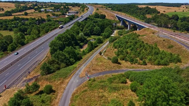 Forward drone fly toward regional L'Armoricaine highway bridge interchange hub during daily traffic surrounded by green countryside, Change, Mayenne, France