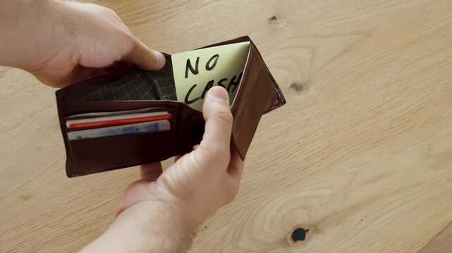 A man opens his wallet and finds a note reading "No Cash" instead of money. Concept of financial hardship, empty wallet, budgeting, and lack of cash.