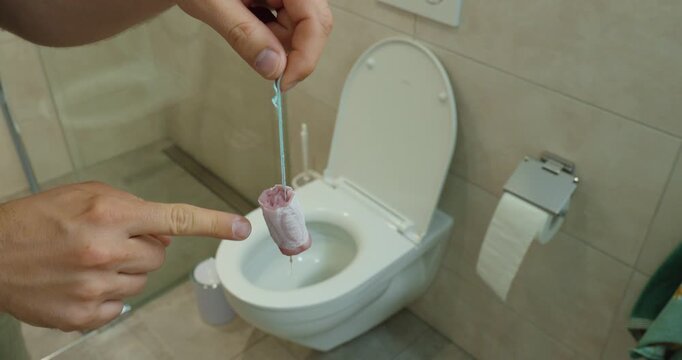 A person demonstrates that tampons should not be flushed down the toilet. Concept of proper sanitary product disposal, plumbing protection, bathroom hygiene, and environmental awareness.