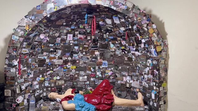 Difunta Correa shrine filled with plaques and devotional offerings, establishing downward tilt