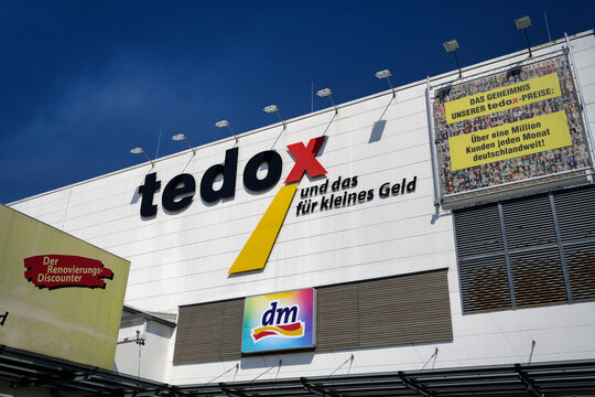 Cologne, Germany August 14 2026: Exterior view of a commercial building facade with Tedox and dm store logos under a clear blue sky in Cologne-Marsdorf, Germany