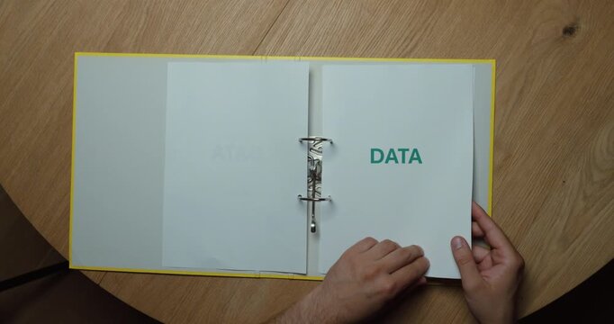 A person flips through a binder where every page is labeled "DATA." Concept of data management, information organization, documentation, and business records.