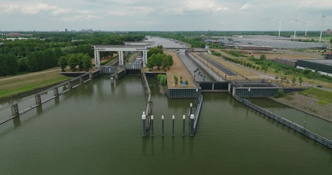 Drone horizontally tracks leisure boats and a tanker barge waiting inside a sluice chamber for the gate to open, allowing vessels to continue their journey along the river.