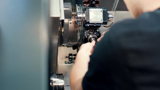 Worker operating a CNC turning machine in a metal workshop