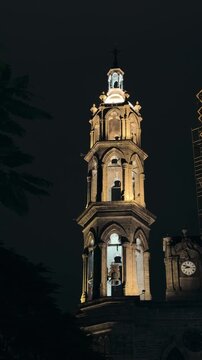 Bell tower of Tepic Cathedral at night in Nayarit, Mexico brightly illuminated against dark sky