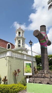 Cross of Zacate monument beside church under blue skies in Tepic Nayarit, vertical establishing