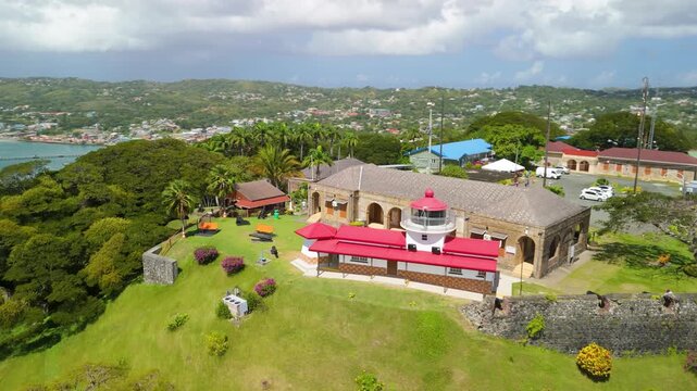 Aerial orbit shot of Fort King George historic hilltop fort in Scarborough Tobago featuring colonial barracks lighthouse cannons tropical gardens and panoramic bay views