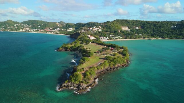 Orbit shot around Quarantine Point peninsula, green headland surrounded by turquoise sea near Grand Anse, Grenada