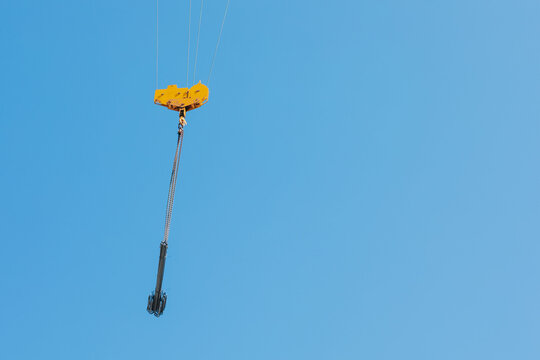 Suspended Crane Hook and Rigging Against Clear Blue Sky