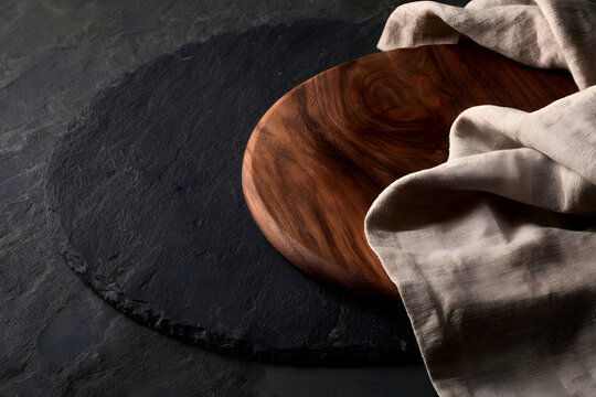 The dining table made of dark stone, equipped with a cutting board and a linen napkin