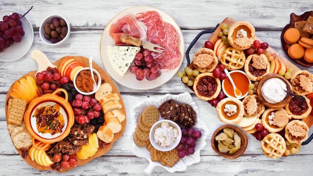 Autumn or Thanksgiving appetizers, sweets and grazing boards. Overhead view stop motion animation placement on a white wood background. Pumpkin and apple snacks, charcuterie, pies, desserts.