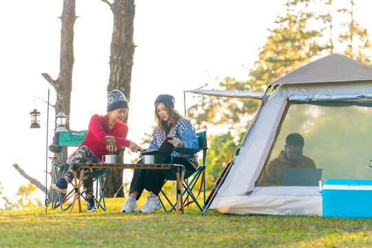 Group of Asian man and woman remote working corporate business meeting discussion while travel nature camping on the mountain with drinking coffee. Digital nomad workation outdoor active lifestyle