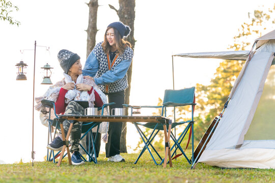 Asian woman colleague remote working corporate business meeting discussion with using digital tablet while camping on the mountain with drinking coffee. Digital nomad workation outdoor lifestyle