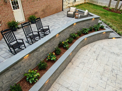 Elevated Angle Of Curved Stone Retaining Wall With Integrated Lighting And Patio Seating