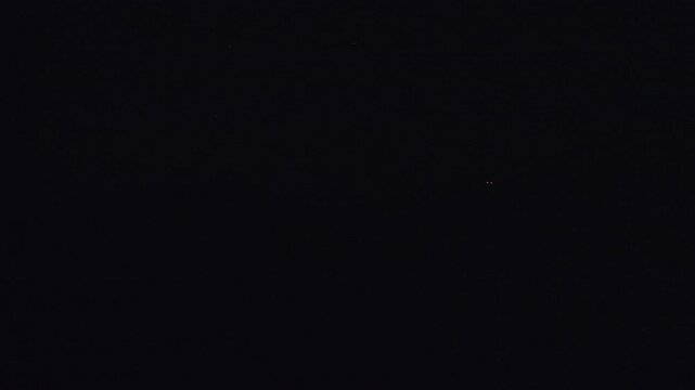 The glowing red‑and‑white trails of tracer bullets from an anti‑aircraft machine gun in the dark night sky. High quality 4k footage