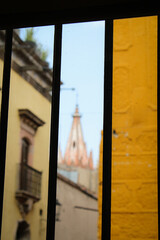 Fototapeta premium A traves de la ventana, barrotes de un restaurante por donde se ve la parte más alta de la iglesia de San Miguel de Allende , guanajuato.