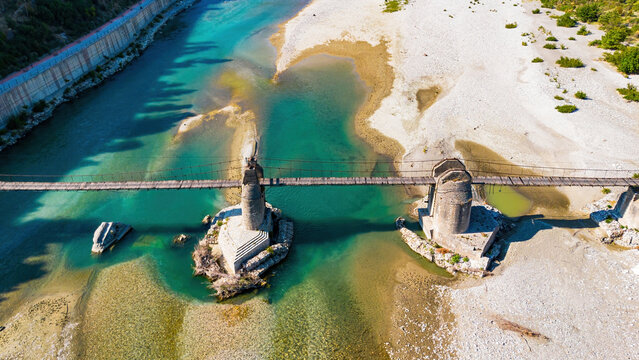Aerial drone view of the historic Ali Pasha Bridge ruins spanning the wide, meandering Vjosa River bed in Tepelene, Albania