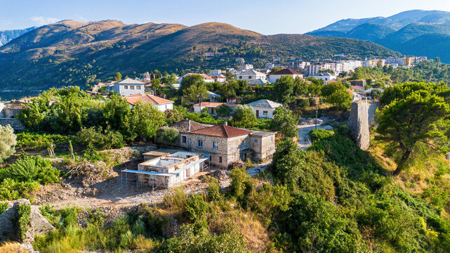 Aerial view of residential houses within Telepene Castle in front of rolling hills in Albania