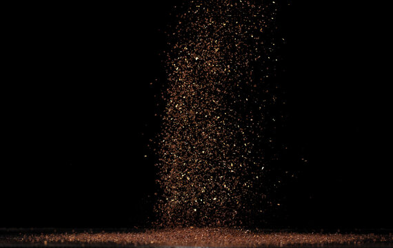 Roasted Coffee powder ground dust splash explosion in mid Air. Ground Coffee roasted powder dust fly explosion, Coffee crushed ground float pouring. Black background Isolated