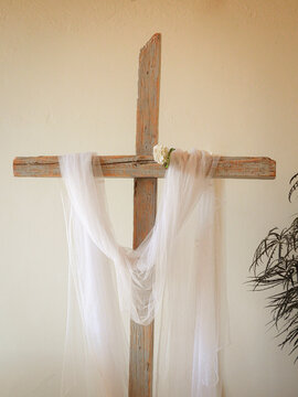 Cruz de madera en iglesia para altar, adornada con una tela de gasa blanca durante una boda