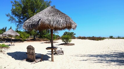 Fototapeta premium Thatched Umbrellas and Wooden Chairs on White Sand Beach in Madagascar