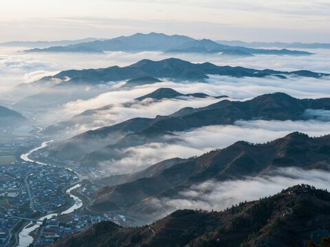 Mountain ranges and river valley town seen above sea of clouds