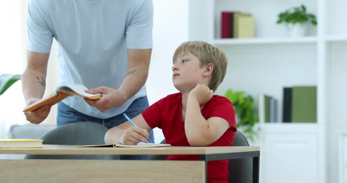 Father scolding his son while helping with homework at wooden table indoors, closeup