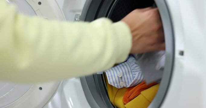 Woman loading washing machine and adding laundry detergent, closeup. Camera moving