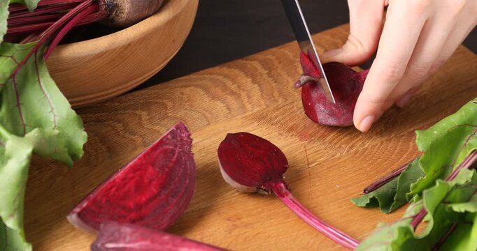 Woman cutting fresh young beet at table, closeup