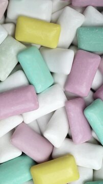 Close-up of colorful pastel chewing gum pieces in pink, mint, yellow, white and purple. Soft chewy texture.