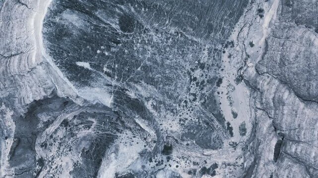 Top-down aerial view of rugged eroded badlands and dry canyon landscape, highlighting natural Earth geology, textures, and mountain topography for nature films.
