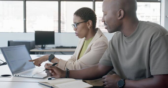 Coworkers, woman spotting laptop line, pointing and explaining at desk while man noting in notebook