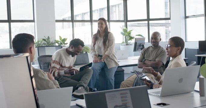 Diverse casual team reacting to notebook flip for review, tablet user showing mockup at office