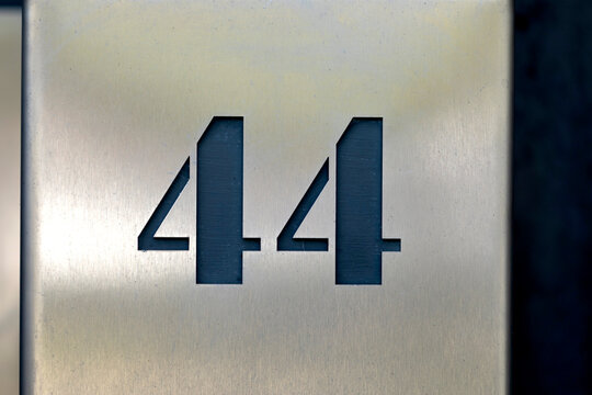 Number fortyfour cut from stainless steel for address label on house. Number on light steel background
