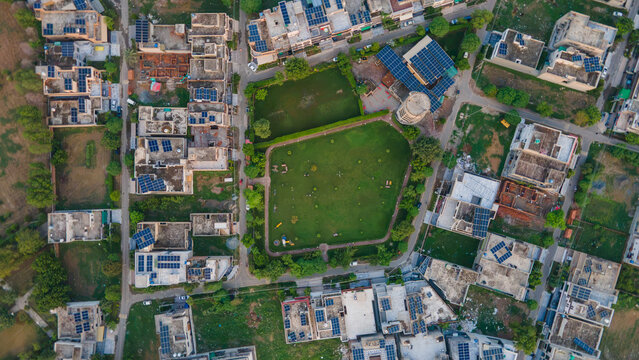 Aerial view of a residential neighborhood with a central green park and houses featuring solar panels on rooftops in Lahore, Punjab, Pakistan.