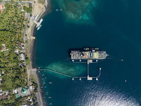 Aerial view of a Floating Storage and Offloading Ship moored offshore with a long pier extending from the coastline in Buleleng Regency, Bali, Indonesia.